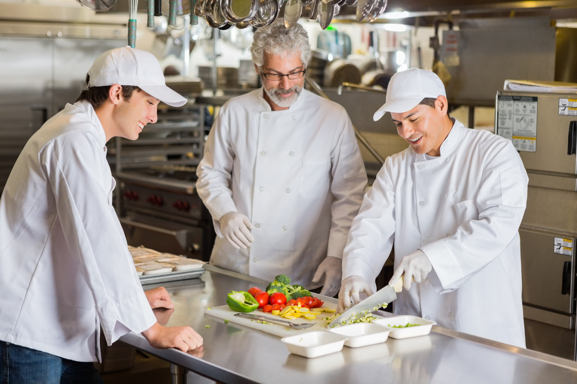 Cooking instructor teaching culinary students in commercial kitchen